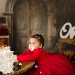 Let them eat cake! A first birthday cake smash is pure, messy, joyful chaos. This little one in her beautiful red dress didn't hesitate to dive right in, creating the most adorable memories of her big day.