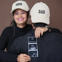 Officially Mom and Dad. This creative shot with "Mom" and "Dad" caps and the ultrasound scan is a fun and modern way to announce your new roles to the world.