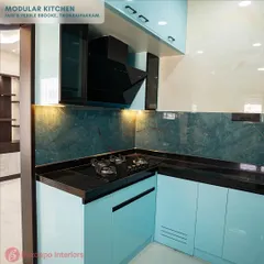A closer look at the cooking area in this light blue kitchen. The black chimney hood is neatly integrated between the overhead cabinets, and under-cabinet lighting ensures the workspace is always well-lit.