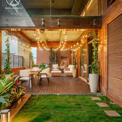 This view of the covered patio at Windmills of Your Mind shows the seamless transition from indoor to outdoor living. The wooden deck, string lights, and climbing vines create a cozy, inviting atmosphere for evening relaxation.