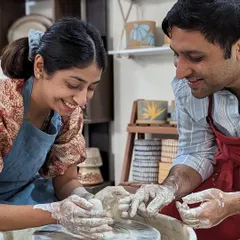 Guiding a partner's hands on the wheel is a classic pottery moment. It's a fun challenge in teamwork and makes for a great photo.