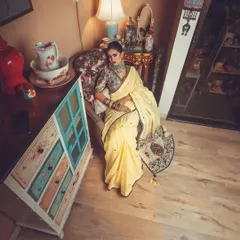 An overhead shot from the vintage-themed ethnic shoot. The model is styled in the yellow saree with an embroidered jacket blouse, showcasing how the outfit drapes beautifully even when seated.