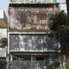 The full elevation of the '10x10 Residence', where layers of perforated screens and wooden louvers create a visually rich and functional facade.