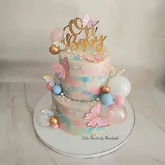 A beautiful two-tier baby shower cake in a swirl of pink and blue. This no-fondant design is decorated with butterflies and bubbles for a dreamy, magical feel.