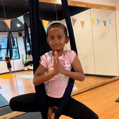 A moment of peace and poise. This young girl finds her center while sitting in the aerial hammock, demonstrating the calm and focus that these classes can bring.