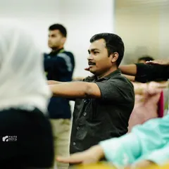 Employees participating in a gentle arm-stretching exercise during a wellness workshop. These movements are designed to release tension in the upper body, a common issue in corporate environments, helping to alleviate neck and shoulder pain.