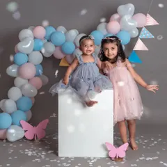 Sisterhood is a beautiful thing. These two sisters look adorable in their matching tulle dresses, posing with a fun balloon arch and confetti.