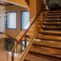 A staircase is a central feature that can transform a space. This design combines elegant marble treads, a wooden handrail, and a glass balustrade, enhancing the overall aesthetic of the home.