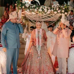 The bride's entry under a delicate 'phoolon ki chadar' (floral canopy) that I designed to match the main mandap decor. It's these cohesive details that make the ceremony feel complete.