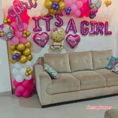 An "It's a Girl" celebration corner. This setup features a vibrant balloon arrangement in pink, gold, and white, with foil letters and baby-themed balloons, perfect for capturing photos of this happy milestone.