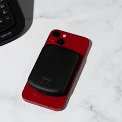 A lifestyle shot of an Urbn power bank charging an iPhone. This image demonstrates the product's use case in a realistic, everyday setting.