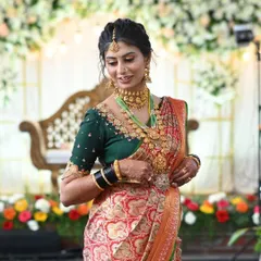 A stunning bride in a red and green silk saree, paired with a custom dark green blouse featuring intricate neckline embroidery. This is a classic color combination for a wedding muhurtham.