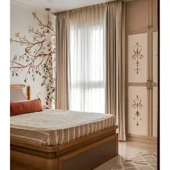 In the parents' bedroom, a delicate floral mural on the wall harmonizes with the custom hand-painted wardrobe shutters. The soft, earthy color palette keeps the space calm and restful.
