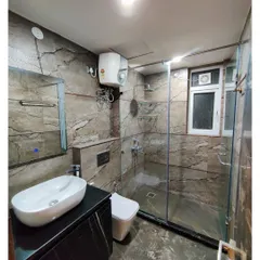 This modern bathroom uses large-format, stone-patterned tiles on the walls and floor for a dramatic effect. The glass shower partition and floating black vanity create a clean and spacious feel.