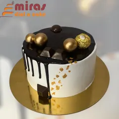 A modern and chic chocolate drip cake. It's topped with Ferrero Rocher, chocolate spheres, and gold leaf for a touch of luxury, perfect for any office celebration.