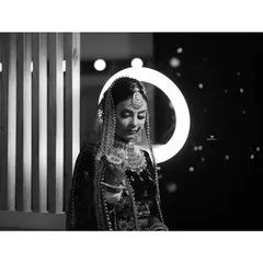 A stunning black and white bridal portrait using a ring light to create a beautiful halo effect. The contrast between the illuminated bride and the dark background makes for a striking and modern photograph.