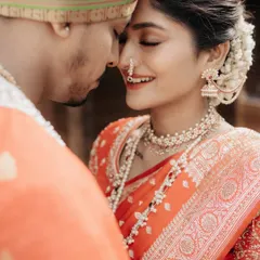 A close-up, tender moment between a Marathi bride and groom, highlighting the bride's beautiful smile and traditional nose ring.