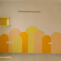 A finished mural in a child's room featuring overlapping arches in warm shades of yellow, peach, and orange. This simple geometric design is modern, cheerful, and stimulates creativity.