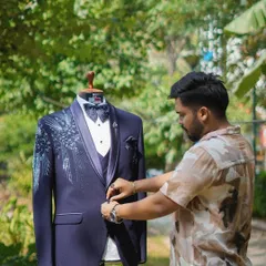 The process of creation is my passion. Here I am adjusting the button on a custom-designed tuxedo, ensuring the fit and fall is absolutely perfect before it reaches my client.