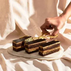 The Opera Cake is a French masterpiece. It features thin layers of almond joconde, coffee buttercream, and rich chocolate ganache, creating a perfect harmony of flavors.