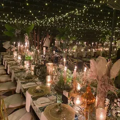 There is magic in the details. I designed this whimsical dining experience under a canopy of countless fairy lights, creating the illusion of a starry night sky. The warm glow of hundreds of candles on mirrored tables adds to the enchanting, intimate atmosphere for a truly memorable reception.