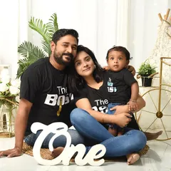 A family celebrating their child's first birthday with matching "The Boss" and "The Real Boss" t-shirts. This fun concept, complete with a "One" prop, adds personality to the milestone shoot.