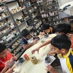 A group of young artists hard at work during a birthday party. Here, the kids are focused on painting their hand-built clay bowls, each adding their own unique touch.