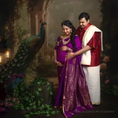 An expecting couple stands in a regal, vintage-inspired studio setting with a painted peacock backdrop. This traditional maternity portrait is rich with cultural elegance and artistry.