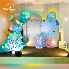 We dove deep to create this magical underwater world for a first birthday party. The setup features a custom backdrop with adorable sea creatures, an organic balloon garland in shades of ocean blue and teal, and charming cutouts of coral, a seahorse, and an octopus. The glowing "1" marquee light adds a special touch to this enchanting aquatic theme.