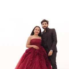 A full-length view of the gorgeous maroon ball gown against a clean, bright background. This minimalist approach really makes the couple and the detailed outfit pop.