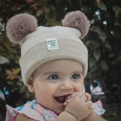 A baby's smile can make a house shine without the sun. This close-up portrait captures the pure, heart-melting happiness of a baby in a cute pom-pom hat.