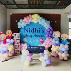 A cute baby shower setup with a custom backdrop and cartoon baby cutouts. The pastel balloons and 'BABY' blocks are perfect for the occasion.
