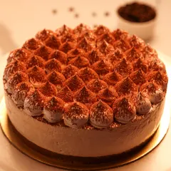We present a taste of Italy with our classic Tiramisu cake. Featuring layers of coffee-soaked ladyfingers and creamy mascarpone, this cake is finished with piped cream and a generous dusting of cocoa powder for an authentic and elegant dessert experience.