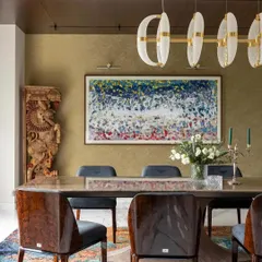 This dining room blends traditional and modern elements. A carved wooden artifact stands beside contemporary artwork, while a sleek pendant light illuminates the space. It’s a perfect example of how I integrate a client's existing treasures into a new design.