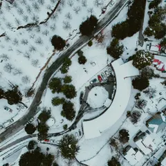 A view from my DJI Mini 4 Pro. I love using my drone to capture the sheer scale and patterns of a landscape, like this stunning top-down aerial of a snow-covered village and winding road.