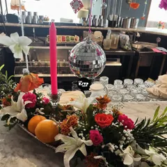 A close-up of the bar decor, featuring a stunning floral arrangement with fresh oranges, a pink candle, and a mini disco ball.