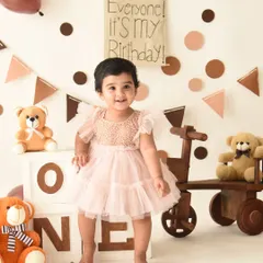That beautiful smile says it all. This first birthday portrait captures a moment of pure happiness amidst a charming teddy bear party setup.