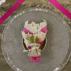 A close-up of a place setting from my pink ribbon-themed tablescape. The pink napkin, held in a delicate lace and burlap bouquet, sits on a silver placemat, creating a look of elegance and hope.