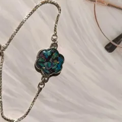 This image shows a beautiful bracelet made from preserved orchid petals. The silver flower-shaped setting perfectly complements the deep blue and purple of the petals.