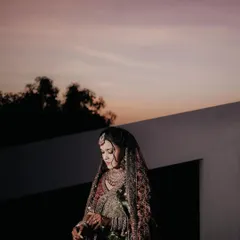 A stunning portrait of a bride in her intricate lehenga, captured against the soft colors of a sunset sky.