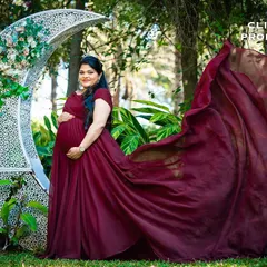 A fairy-tale moment with the mother-to-be posing next to a crescent moon prop. The flowing gown and whimsical set piece combine for a magical maternity photograph.