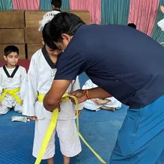 The journey begins with the first belt. Here I am tying a yellow belt on a young student, marking the first step in their Taekwondo journey.