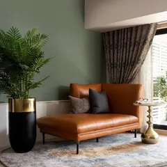 A cozy lounging corner featuring a tan leather chaise against a military green accent wall. This shows how I use color blocking and luxurious textures to create intimate, relaxing zones within a larger living area.