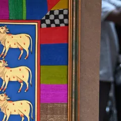 A detail shot of the fabric border on the Pichwai frame. You can see the different textures and colors of the pieced-together scraps, including a bold checkerboard pattern that adds a graphic element.