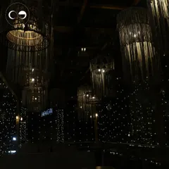The interior of a restaurant transformed for a festive celebration. A canopy of fairy lights and beautifully lit rattan chandeliers created a starry night effect, adding a warm and magical glow to the entire space.