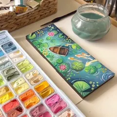 A beautiful gouache painting of a lily pond, complete with a small wooden boat. This piece was inspired by peaceful, dreamy landscapes and is filled with details like koi fish, lily pads, and pink water lilies.