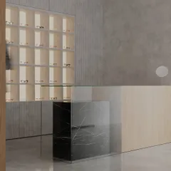 A different angle of the clinic's reception, showing the interplay of textures. The smooth concrete floor, ribbed wall panels, and warm wood create a tactile experience that is both minimalist and aesthetically rich.