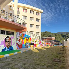 A wide shot of the 100-foot mural at St. Claret College, Ziro. The artwork spans the length of the building, featuring portraits of historical figures and colorful abstract designs that completely transformed the campus.