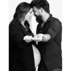 A creative black and white shot of an expecting couple holding a tiny pair of glasses, symbolizing their growing family. This is a sweet and personal way to announce your pregnancy.