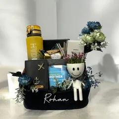 A beautifully arranged Rakshabandhan hamper for a brother, personalized with his name. This gift basket includes a 'World's Best Brother' item, a custom passport cover, a water bottle, and other thoughtful treats.